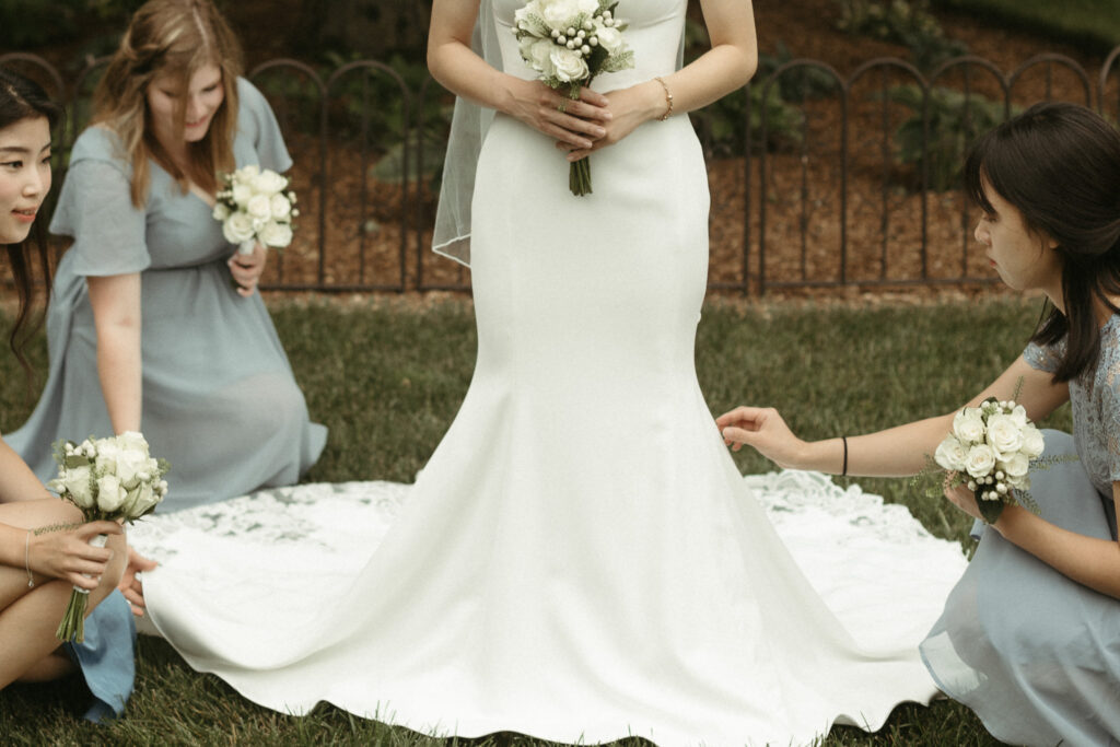 Photo of a bride having her dress fixed. Editorial Styled Wedding Photo. Fine Art Wedding Photographer in Michigan 