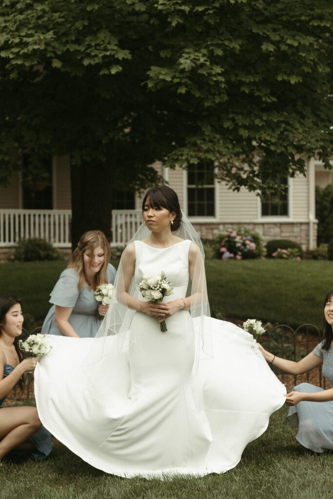 Photo of a bride having her dress fixed. Editorial Styled Wedding Photo. Fine Art Wedding Photographer in Michigan 