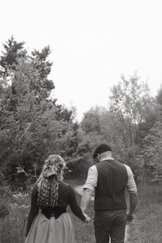 A man and a woman walking down a mIchigan forest path in a cottagecore skirt.