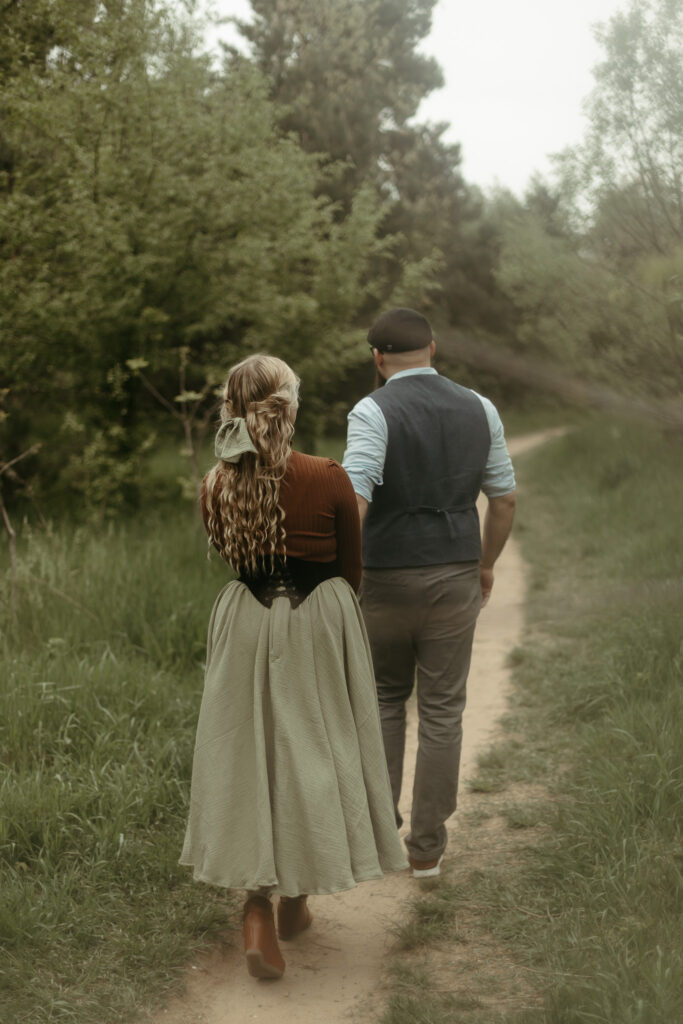 A man and a woman walking down a Michigan forest path in a cottagecore skirt