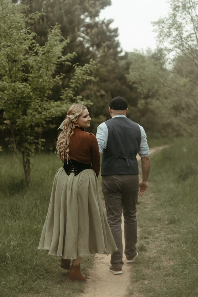 A man and a woman walking down a Michigan forest path in a cottagecore skirt
