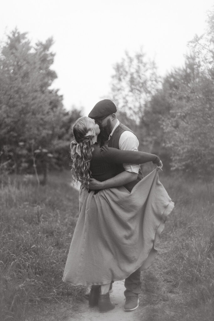 A man and a woman kissing while she holds her cottagecore skirt in Michigan
