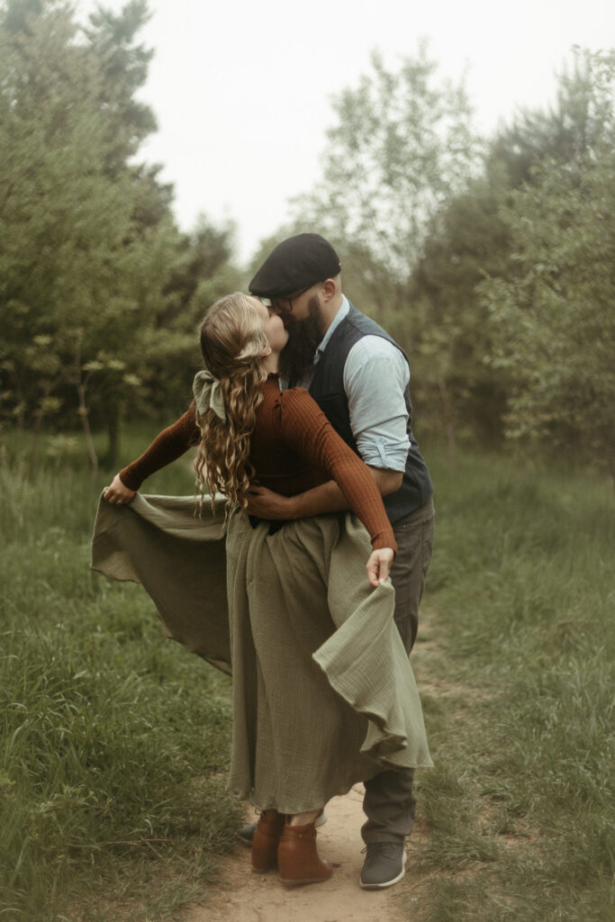 A man and a woman kissing while she holds her cottagecore skirt in Michigan