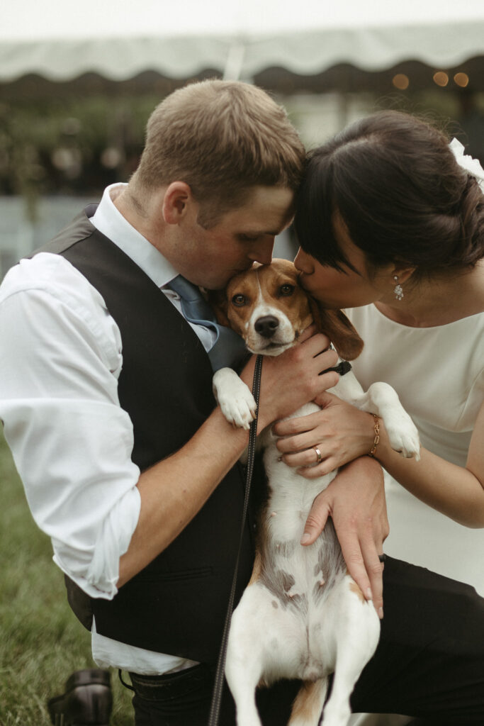 Photo of the bride and groom giving their dog a kiss on the head. . Editorial Styled Wedding Photo. Fine Art Wedding Photographer in Michigan 