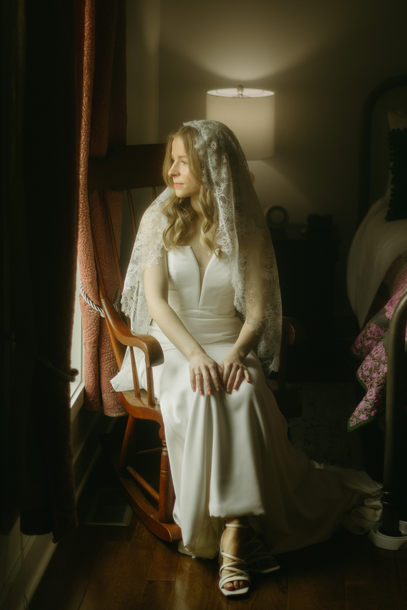 Photo of a bride looking out a window in her wedding dress. Michigan Fine Art Wedding Photographer