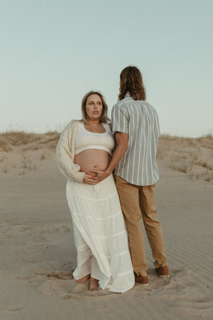 A man and a pregnant woman playing on a Lake Michigan Beach Together