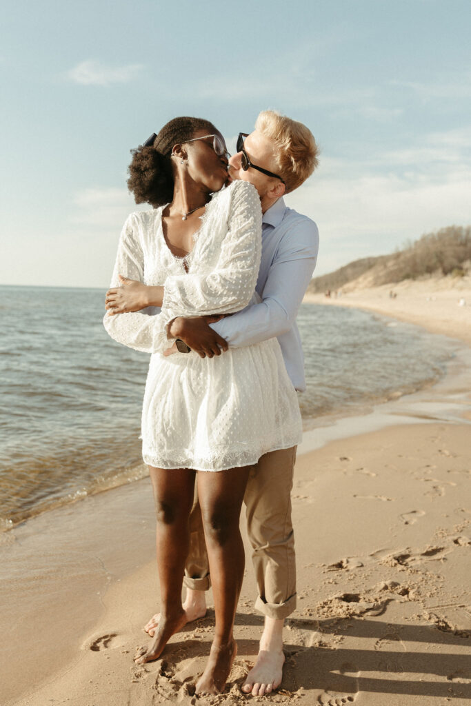 A man and a woman chasing each other around on a beach at lake michigan