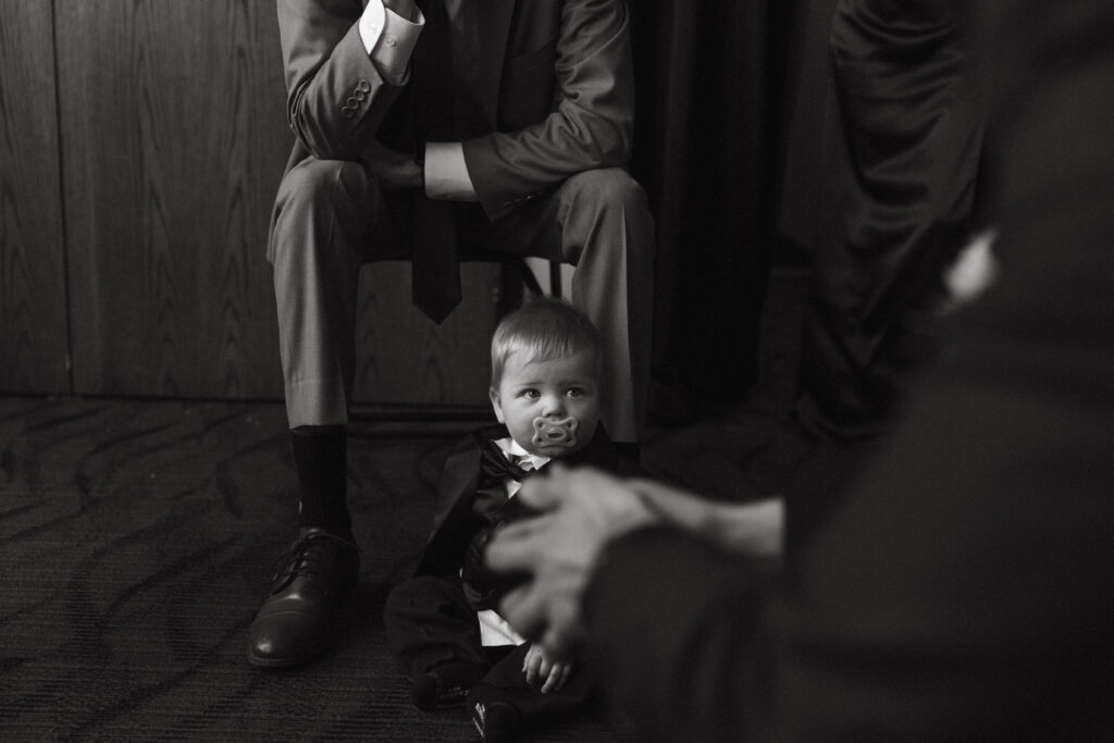 a little baby dressed in a tuxedo for a wedding