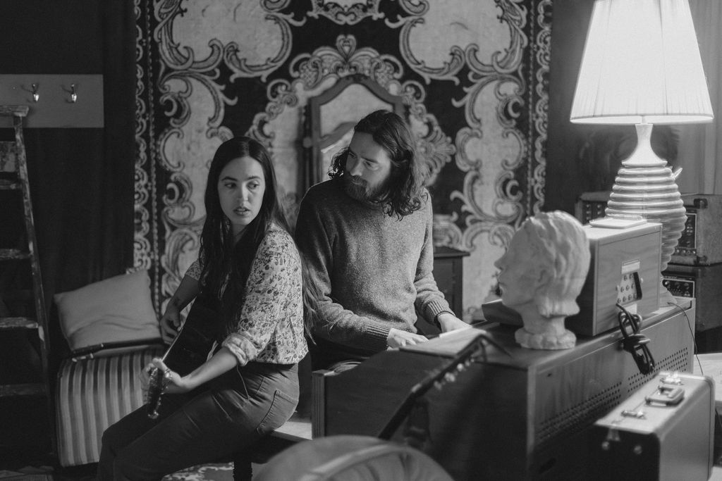 A man and a woman playing music together in a mid century styled air bnb