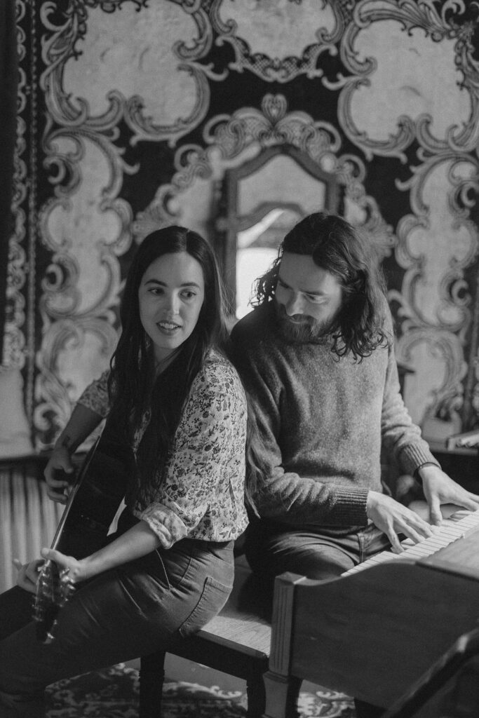 A man and a woman playing music together in a mid century styled air bnb