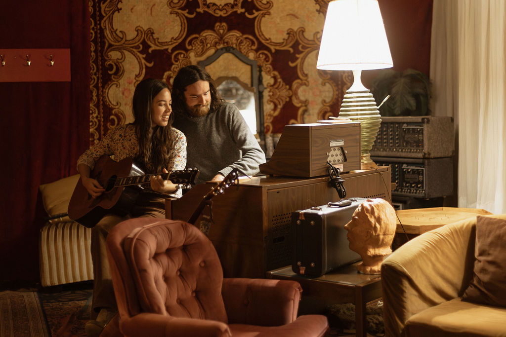 A man and a woman playing music together in a mid century styled air bnb