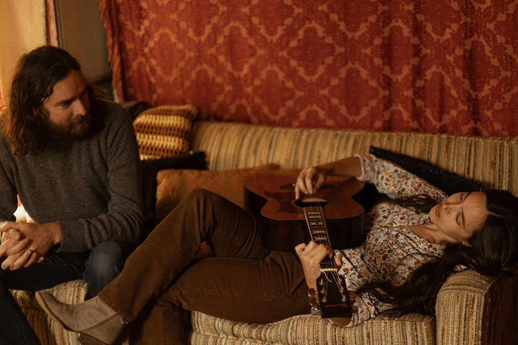 A man and a woman playing music together in a mid century styled air bnb