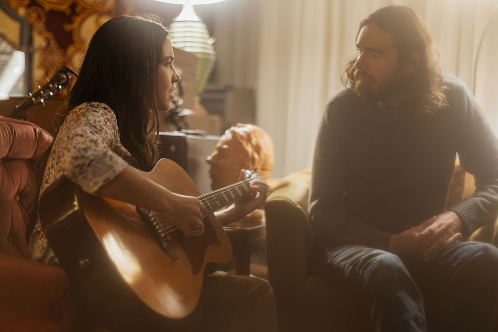 A man and a woman playing music together in a mid century styled air bnb