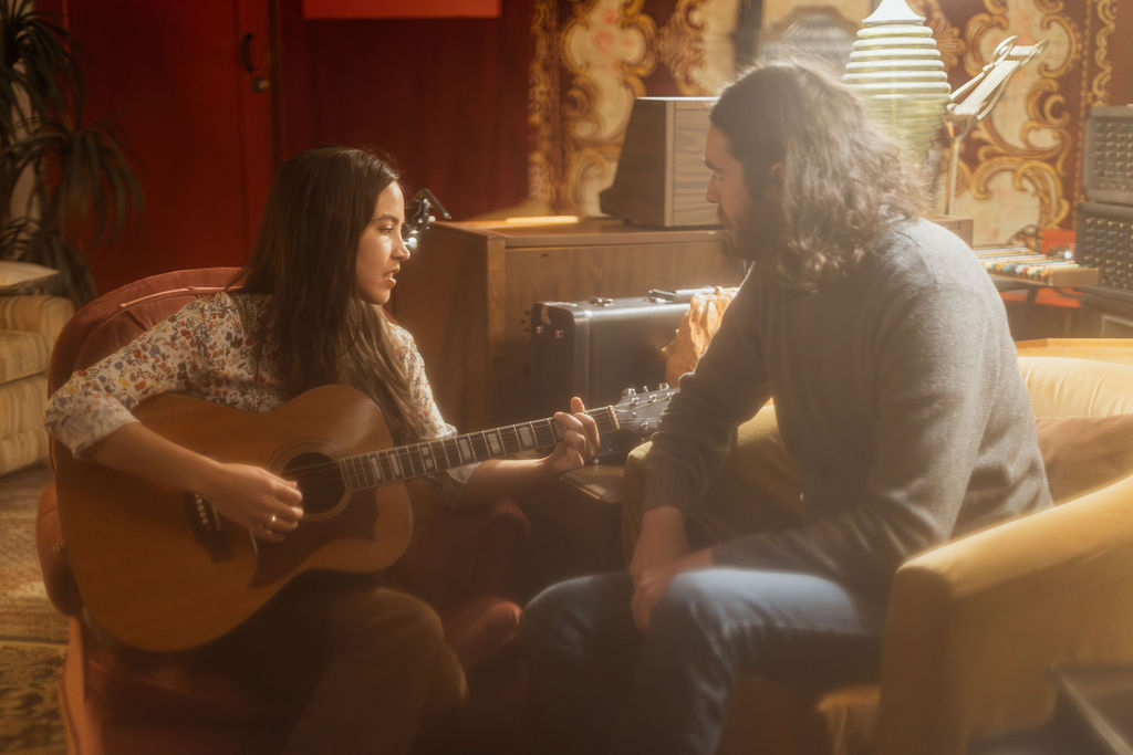 A man and a woman playing music together in a mid century styled air bnb