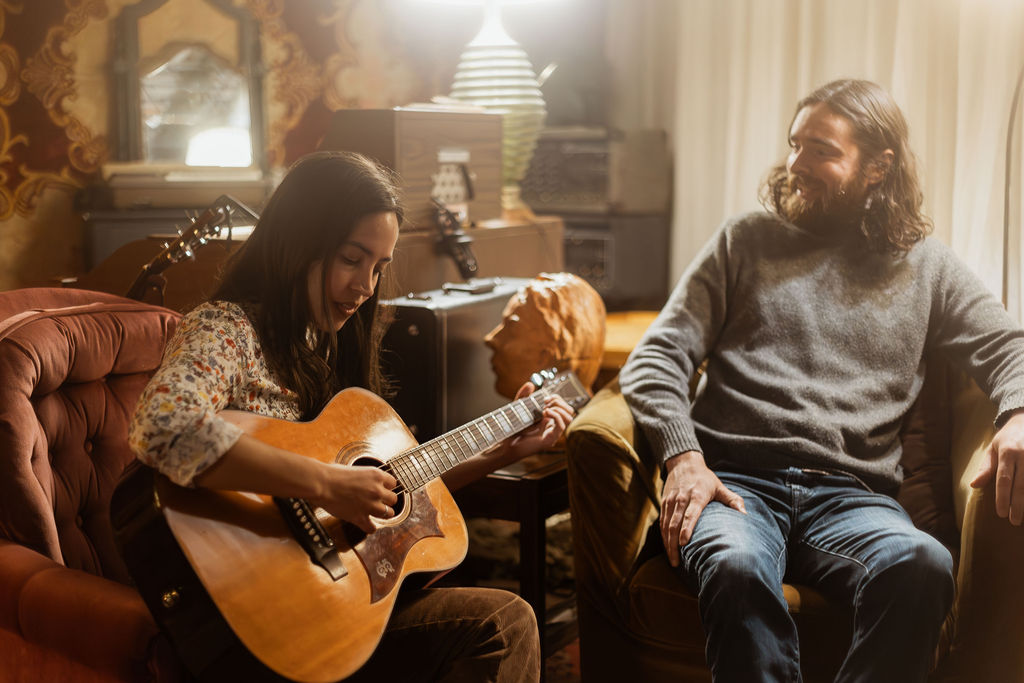 A man and a woman playing music together in a mid century styled air bnb