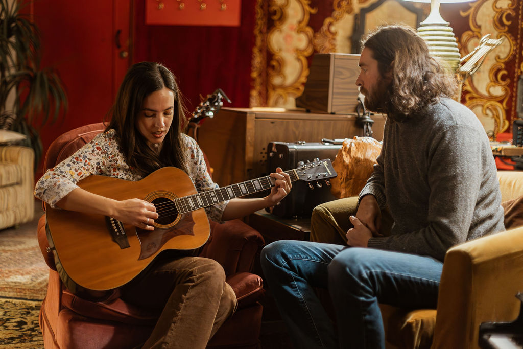 A man and a woman playing music together in a mid century styled air bnb