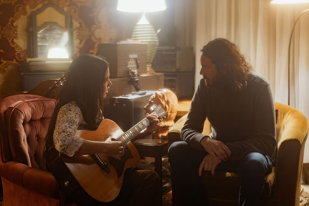 A man and a woman playing music together in a mid century styled air bnb