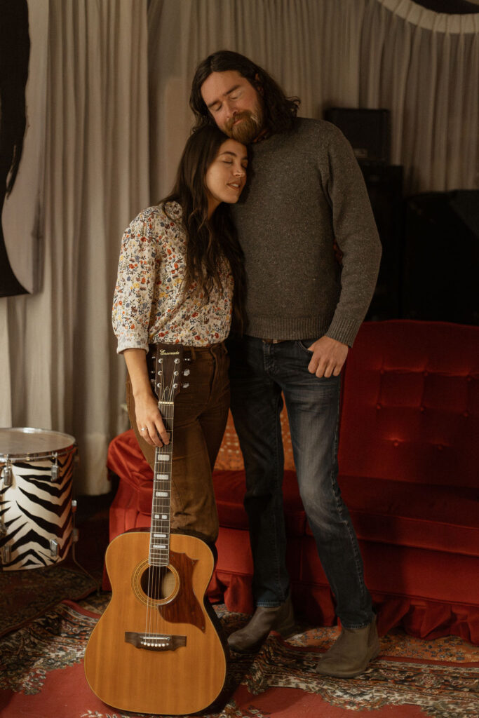 A man and a woman playing music together in a mid century styled air bnb