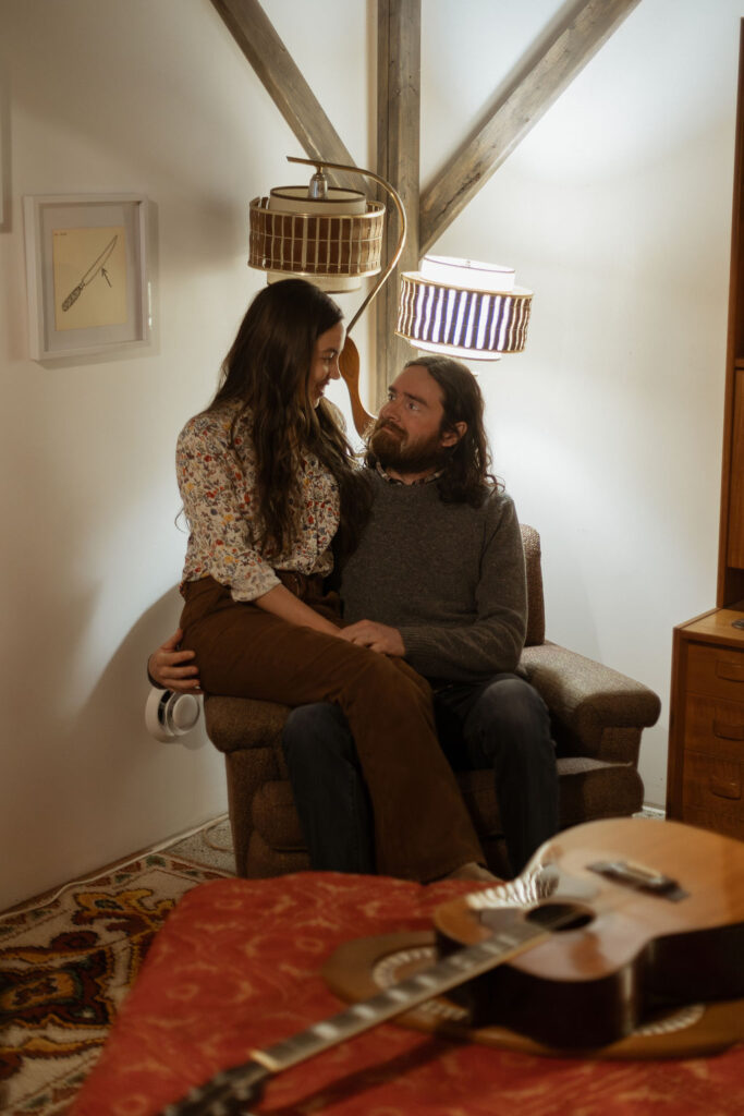 A man and a woman playing music together in a mid century styled air bnb