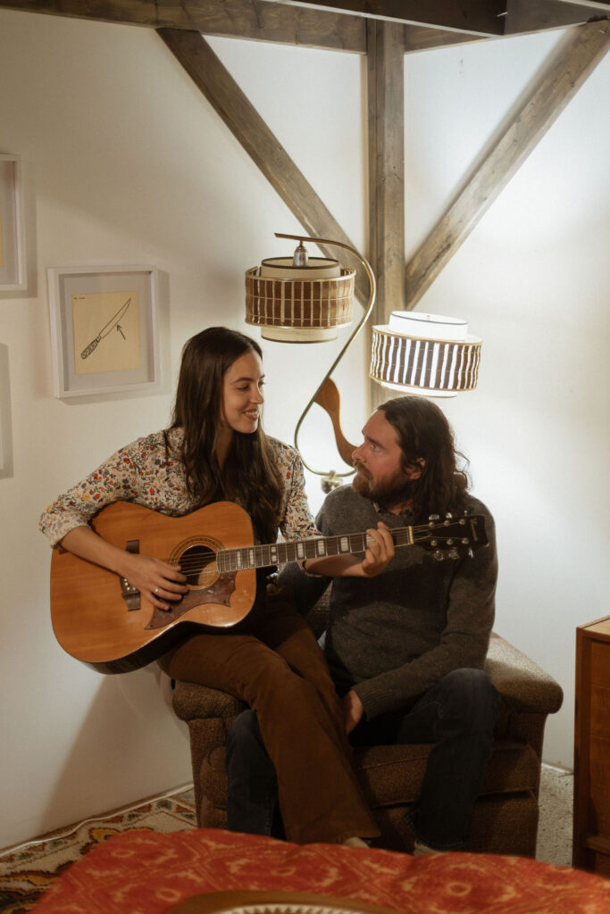 A man and a woman playing music together in a mid century styled air bnb