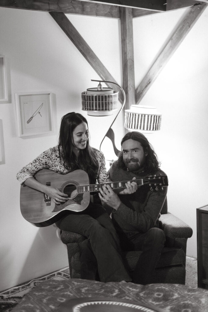 A man and a woman playing music together in a mid century styled air bnb