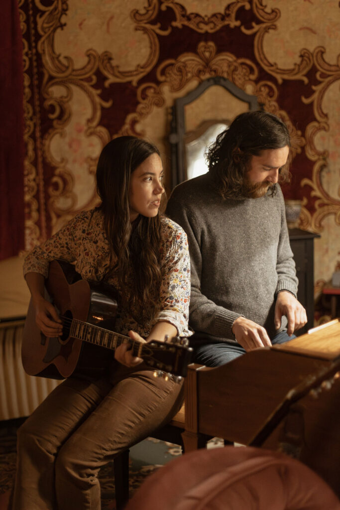 A man and a woman playing music together in a mid century styled air bnb