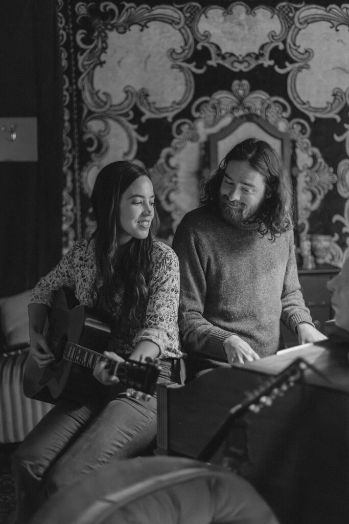 A man and a woman playing music together in a mid century styled air bnb