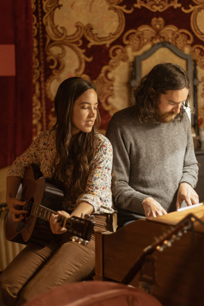 A man and a woman playing music together in a mid century styled air bnb