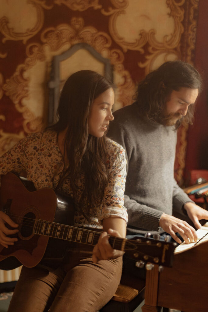 A man and a woman playing music together in a mid century styled air bnb