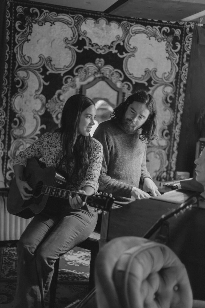 A man and a woman playing music together in a mid century styled air bnb