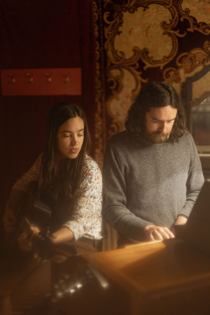 A man and a woman playing music together in a mid century styled air bnb