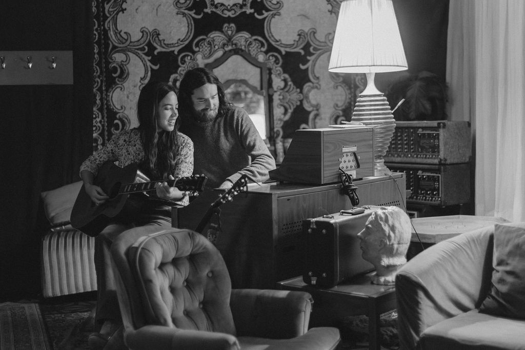 A man and a woman playing music together in a mid century styled air bnb