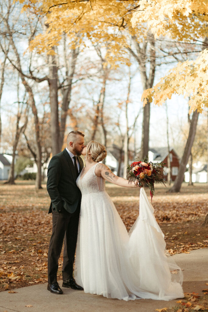 A bride and groom on their wedding day taking photos in the fall