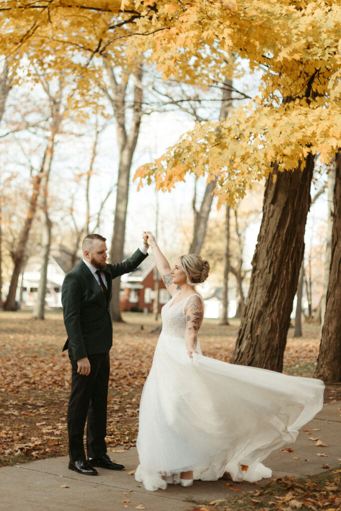 A bride and groom on their wedding day taking photos in the fall