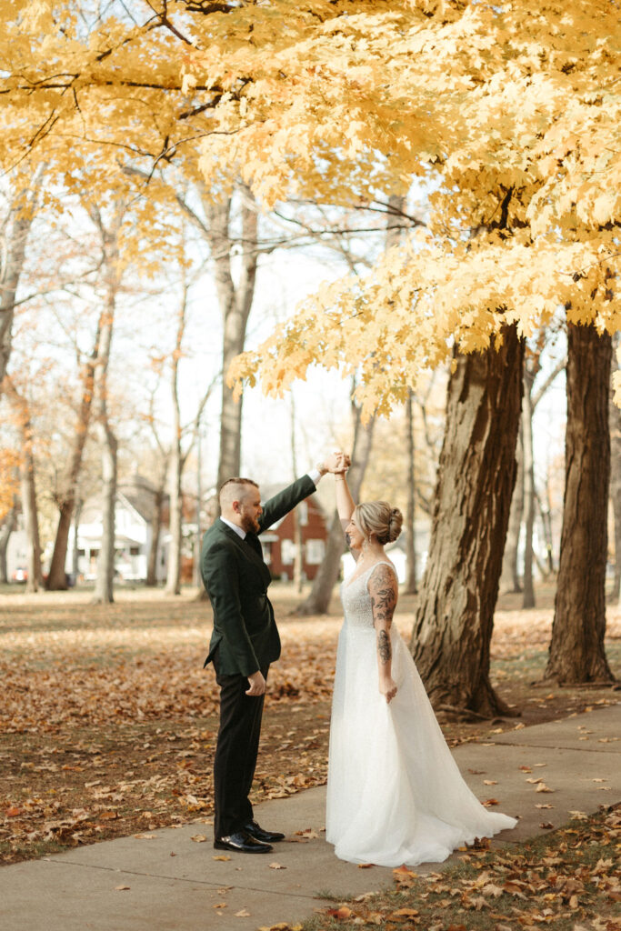 A bride and groom on their wedding day taking photos in the fall