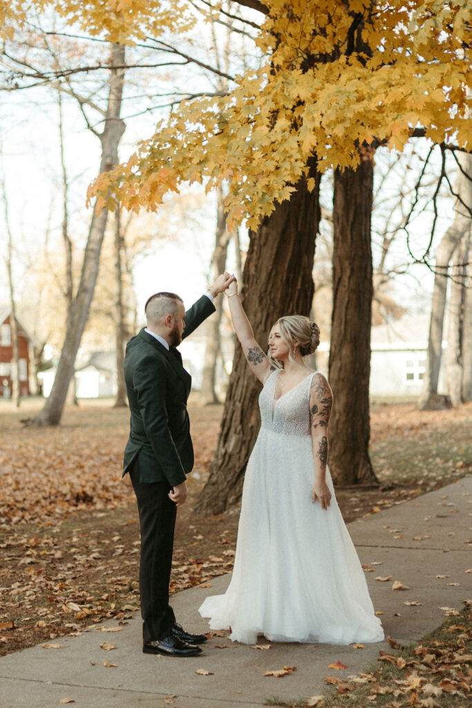 A bride and groom on their wedding day taking photos in the fall