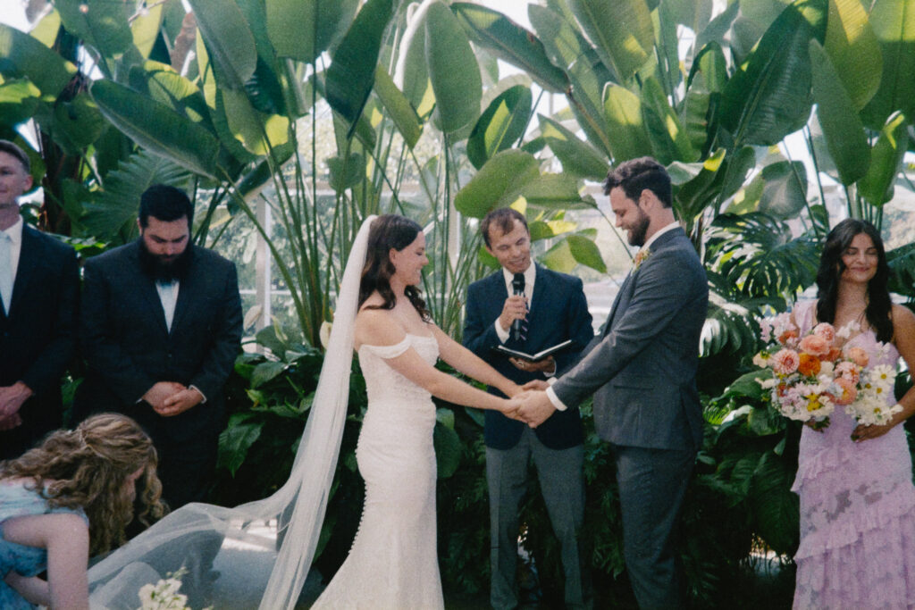 bride and groom holding hands during their wedding ceremony at a greenhouse wedding venue